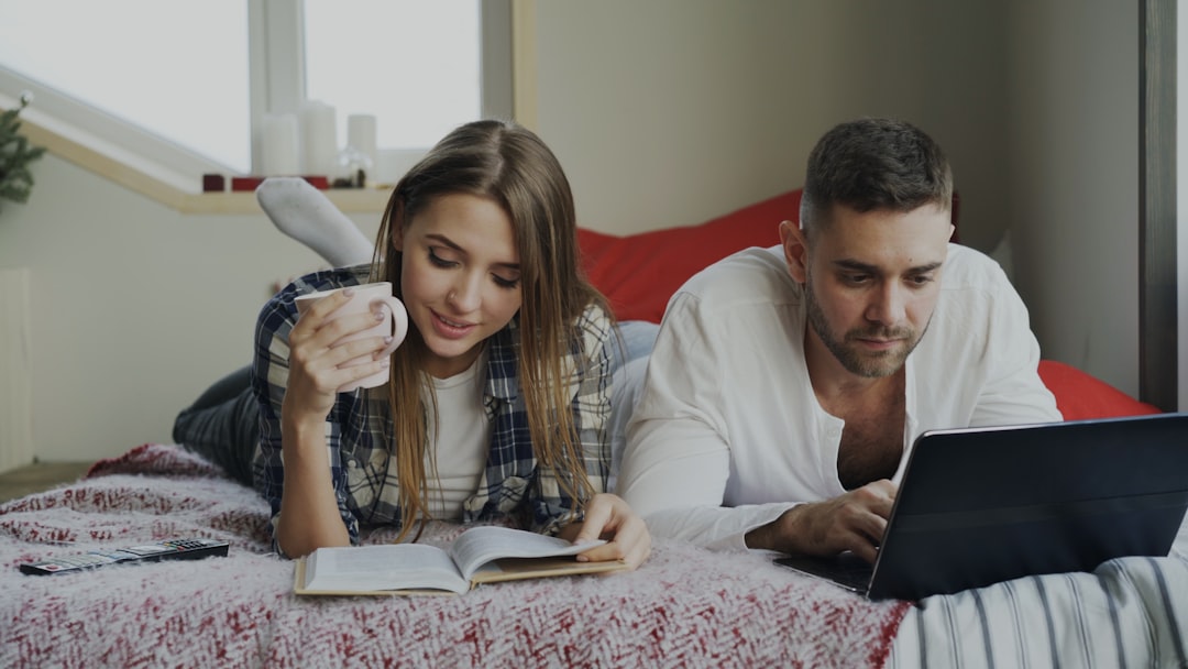 Couple relaxing on bed with book and laptop — Photo by Vitaly Gariev on Unsplash